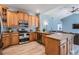 Charming kitchen featuring wood cabinets, granite countertops, stainless steel appliances, and wood-look tile flooring at 4708 Ranch Grove Ct, Valrico, FL 33596