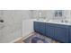 Bathroom featuring blue cabinets, dual sinks, and a glass-enclosed shower with elegant marble-style tiling at 4831 Rosatti Rd, Wesley Chapel, FL 33543