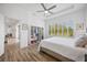 Bright bedroom with wood flooring, tray ceiling, a ceiling fan, and views to a lush green space at 4831 Rosatti Rd, Wesley Chapel, FL 33543