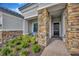 Elegant front entry with stone accents, a black door, and lush landscaping for a welcoming approach at 4831 Rosatti Rd, Wesley Chapel, FL 33543