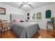 Cozy bedroom featuring a tufted headboard, hardwood floors, and plenty of natural light at 5296 Slater Rd, Spring Hill, FL 34608