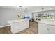 Kitchen island with white cabinets and marble countertops, adjacent to a living area with large windows at 6010 Bayou Grande Ne Blvd, St Petersburg, FL 33703
