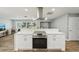 Kitchen with quartz countertops, stainless steel range hood, white cabinets and wood look tile floors at 6010 Bayou Grande Ne Blvd, St Petersburg, FL 33703