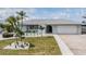 Charming single-story home with a well-manicured lawn, palm trees, and a two-car garage at 7092 S Shore S Dr, St Petersburg, FL 33707