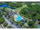 Aerial view of the community pool, tennis courts, and clubhouse surrounded by greenery at 7253 Cleopatra Dr, Land O Lakes, FL 34637