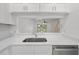 Bright kitchen with white cabinets, countertops and stainless steel dishwasher overlooking living area at 8612 Hunters Key Cir, Tampa, FL 33647