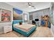 Bright bedroom featuring colorful wall art, a ceiling fan, computer desk, and ample natural light through the window at 915 Tidewater Shores Loop, Bradenton, FL 34208