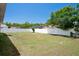 Backyard with a well-maintained lawn, surrounded by a white fence, and mature trees in the neighborhood at 10101 Langan St, Spring Hill, FL 34608