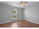 Bedroom with hardwood floors, ceiling fan, and a large window for natural light at 10101 Langan St, Spring Hill, FL 34608