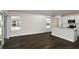 Open living space with dark wood flooring, bright natural light, and a partial view of the modern kitchen at 10516 Hidden Banks Gln, Parrish, FL 34219