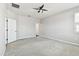 Spacious bedroom with neutral walls, carpet flooring, a ceiling fan and two entry doors at 10628 Massimo Dr, Wimauma, FL 33598