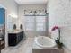 Bright bathroom featuring a soaking tub, double vanity with granite counters, and a decorative accent wall at 1104 Isobel Reserve Ln, Tampa, FL 33613