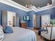 Beautiful bedroom features a tray ceiling, blue walls, and a view into the luxurious ensuite bathroom at 1104 Isobel Reserve Ln, Tampa, FL 33613