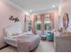 Charming pink bedroom with a white bed, decorative bookcase, and patterned curtains at 1104 Isobel Reserve Ln, Tampa, FL 33613