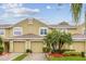 Townhouse featuring attached garage, neutral toned stucco exterior, and tidy landscaping with palm trees at 11162 Kapok Grand Cir, Madeira Beach, FL 33708