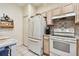 Functional kitchen featuring neutral cabinets, white appliances, tile flooring, and ample counter space at 11162 Kapok Grand Cir, Madeira Beach, FL 33708