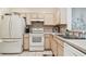 Bright kitchen equipped with white appliances, tile backsplash, and neutral toned cabinetry at 11162 Kapok Grand Cir, Madeira Beach, FL 33708