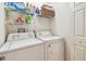 Well-lit laundry room features a washer, dryer, and shelving for storage, creating an efficient and organized space at 11162 Kapok Grand Cir, Madeira Beach, FL 33708