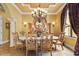 Formal dining room with large table, ornate chairs, decorative lighting, window with curtain and stone floors creates warm ambiance at 11817 Glen Wessex Ct, Tampa, FL 33626