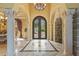 Grand foyer with marble floors, stone archway, decorative columns, wrought iron doors and elegant chandelier at 11817 Glen Wessex Ct, Tampa, FL 33626