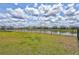 Spacious backyard with lush green lawn and a tranquil pond view, enclosed by a black wrought iron fence at 12710 Hysmith Loop, Parrish, FL 34219
