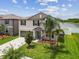 A two-story home highlighting its well-manicured lawn, view of the community lake, and two-car garage at 13529 Wild Ginger St, Riverview, FL 33579