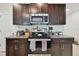 Kitchen with stainless steel appliances, dark cabinets, and granite countertops surrounding electric stove at 13529 Wild Ginger St, Riverview, FL 33579