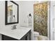 Bathroom featuring a vanity sink, toilet, mirror, and colorful accent wallpaper near the shower at 136 W Davis Blvd, Tampa, FL 33606