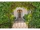 Wrought-iron gate with lush green vines lead to a home's arched front door at 136 W Davis Blvd, Tampa, FL 33606