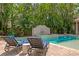 Backyard pool area with a water feature and lounge chairs surrounded by lush greenery in a private setting at 136 W Davis Blvd, Tampa, FL 33606