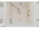 Bathtub with shower in a bathroom featuring white tile and safety grab bars at 1400 Gulf Blvd # 306, Clearwater Beach, FL 33767