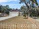 Front exterior view of the house with a large garage, picket fence, and well-maintained lawn at 16519 Us Highway 41, Spring Hill, FL 34610