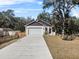 Beautifully maintained exterior of a home with a two-car garage, long driveway, and lush landscaping at 16519 Us Highway 41, Spring Hill, FL 34610