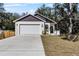 Charming home features a two-car garage, a well-maintained lawn, and a welcoming entrance, all set beneath mature shade trees at 16519 Us Highway 41, Spring Hill, FL 34610