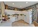 Cozy kitchen featuring white cabinetry, tile flooring, and unique floral wallpaper at 2258 Preservation Green Ct, Sun City Center, FL 33573