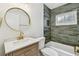Updated bathroom with green tiled shower and round mirror at 3106 Ash Ct, Dunedin, FL 34698