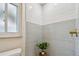 Light blue and white tiled shower with a window and gold shower head at 3106 Ash Ct, Dunedin, FL 34698