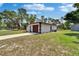 A charming home exterior with a brown garage door, set against a backdrop of lush greenery at 3344 Blythe Ave, Spring Hill, FL 34609