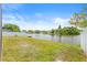 Expansive backyard overlooking a serene lake, bordered by a white fence and lush greenery at 3431 Springfield Dr, Holiday, FL 34691