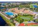 Aerial view showcases a beautiful clubhouse with a pool, putting green, and other community amenities surrounded by greenery at 445 Noble Faire Dr, Sun City Center, FL 33573