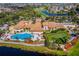 Stunning aerial view of a large clubhouse with a resort-style pool, putting green, and lush landscaping in a golf course community at 445 Noble Faire Dr, Sun City Center, FL 33573
