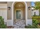 A covered front entrance with a dark green door, and stylish sconce lighting at 4551 Barletta Ct, Wesley Chapel, FL 33543