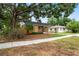 Quaint single-story home with a welcoming front porch, mature trees, and a well-kept yard at 5042 8Th St, Zephyrhills, FL 33542