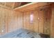 Unfinished room with exposed wood framing, OSB walls and floor, electrical outlets, and a small curtained window at 5042 8Th St, Zephyrhills, FL 33542