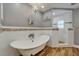 Bright bathroom featuring a soaking tub, decorative chandelier, and tiled shower with shuttered window at 743 Kingston Ct, Apollo Beach, FL 33572