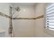 Modern shower with rainfall shower head, tiled walls, and a window with plantation shutters at 743 Kingston Ct, Apollo Beach, FL 33572