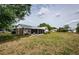 The backyard has a screened patio and is covered with dry grass and a large tree providing ample shade at 7763 Jenner Ave, New Port Richey, FL 34655
