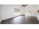 Large living room with gray wood floors, white walls, a ceiling fan, and sliding glass doors at 7763 Jenner Ave, New Port Richey, FL 34655