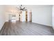 Spacious living room with gray wood flooring, modern fan, and seamless flow to the kitchen at 7763 Jenner Ave, New Port Richey, FL 34655