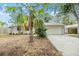 Well-maintained home with a two-car garage, mature palm trees, and a concrete driveway at 1041 Forest Grove Blvd, Palm Harbor, FL 34683
